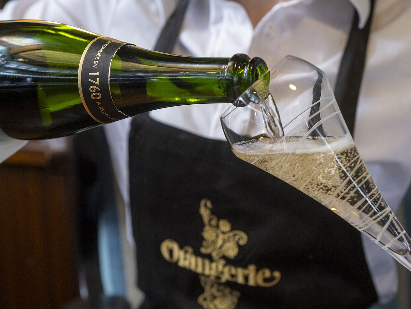 Champagner Champagner wird in ein Glas im Restaurant Orangerie im Maritim Timmendorfer Strand eingeschenkt.