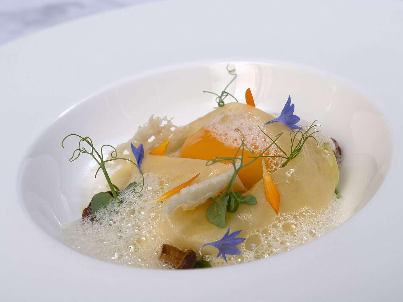 Ravioli Ein Teller mit Ravioli in einer cremigen Sauce, garniert mit essbaren Blüten.