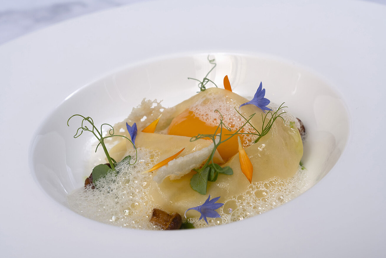 Ravioli Ein Teller mit Ravioli in einer cremigen Sauce, garniert mit essbaren Blüten.