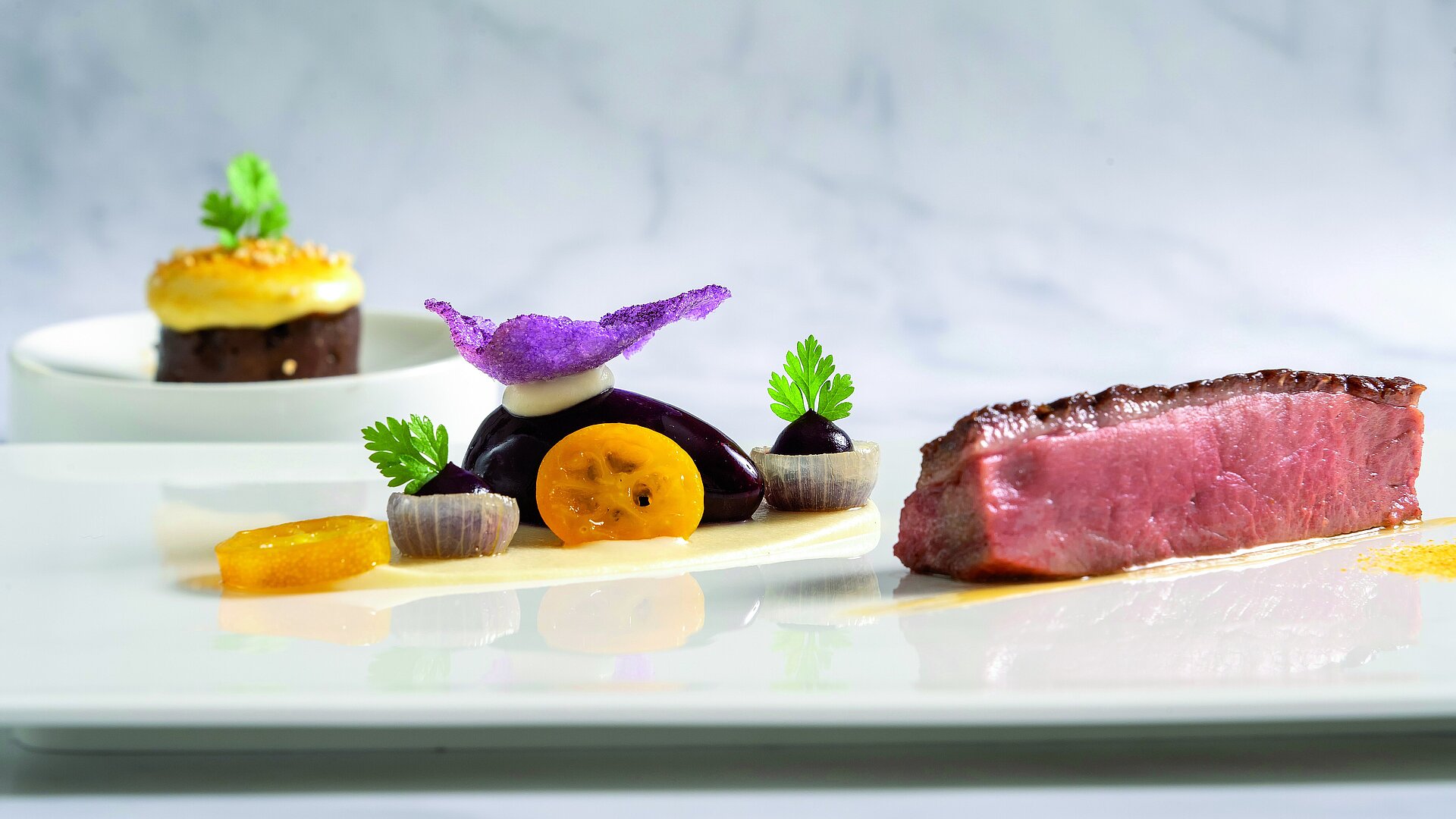 Rinderfilet mit Gourmetbeilage Zartes Rinderfilet mit Gemüsebeilagen und kreativer Gourmet-Dekoration auf weißem Teller