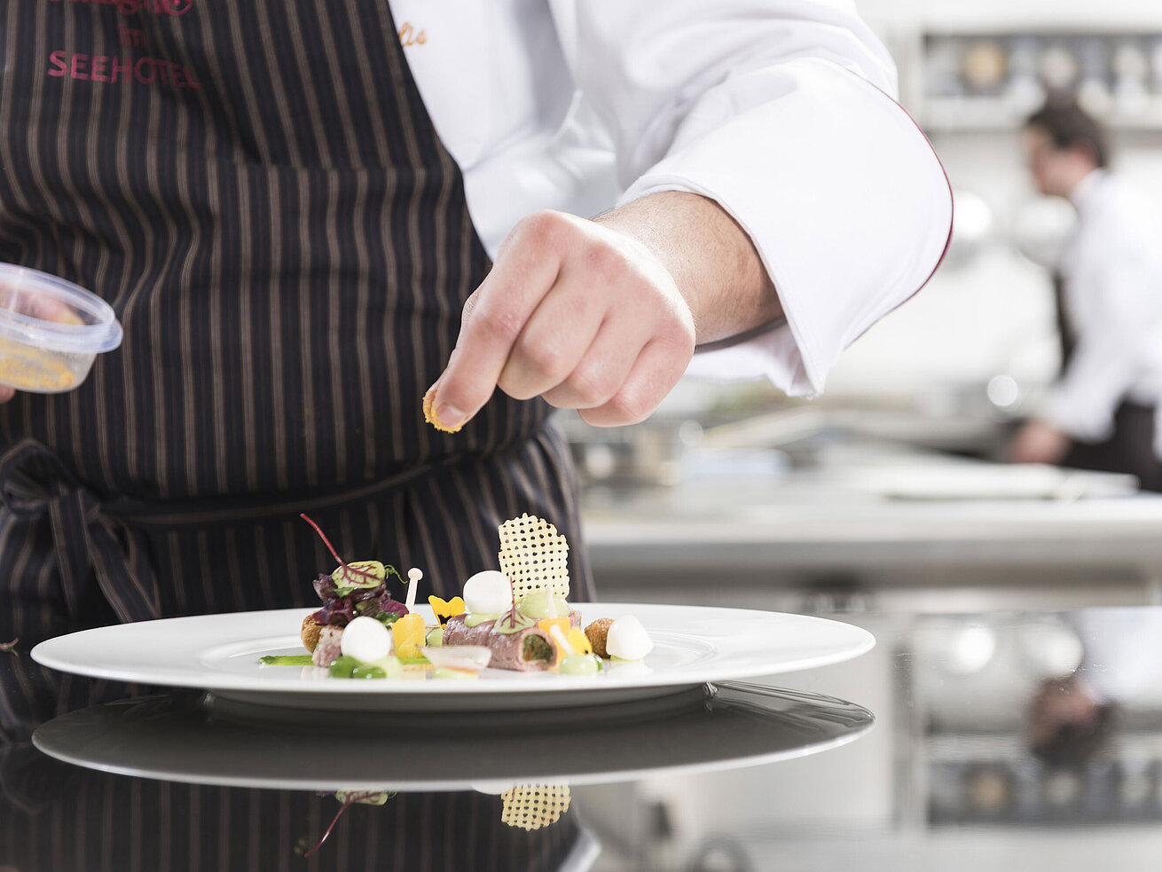 Gourmetgericht Koch richtet ein Gourmetgericht mit Gemüse, Kräutern und kunstvollen Elementen in der Orangerie an.