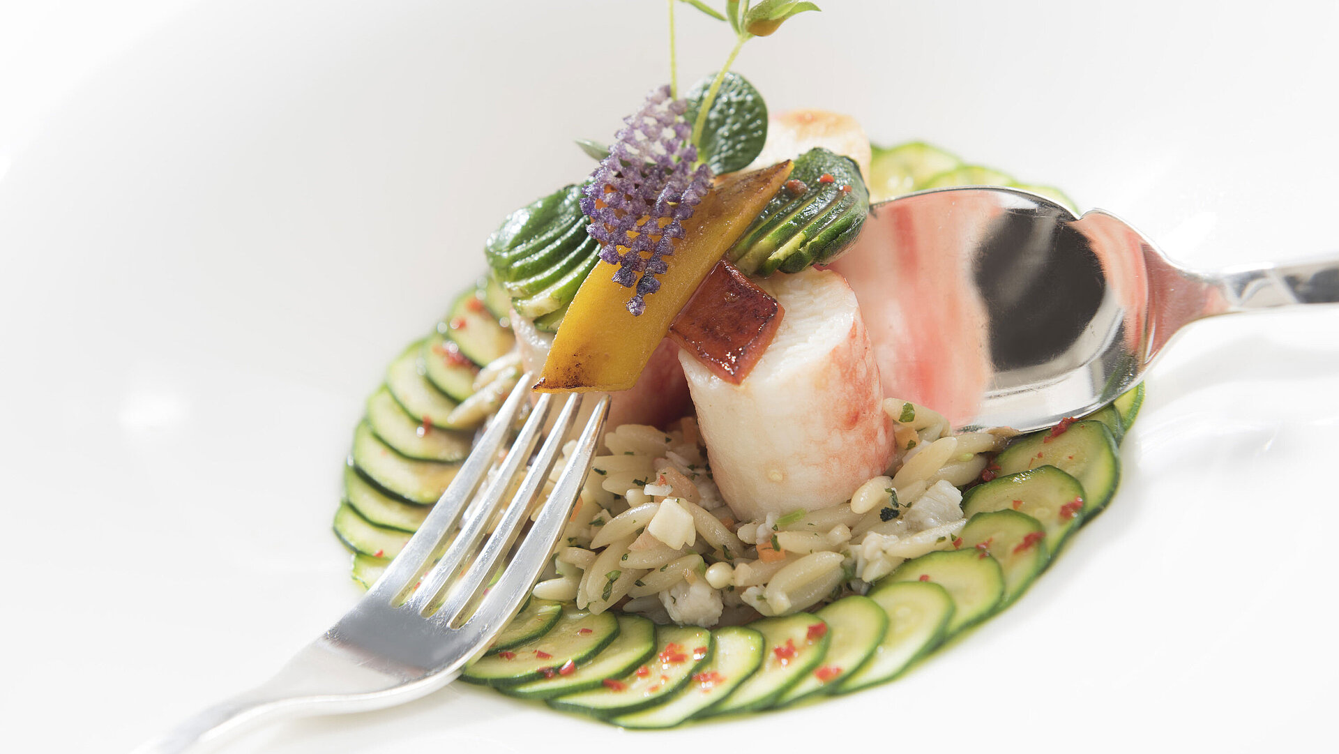 Gourmetgericht Feines Gourmetgericht mit Gurkenscheiben, Reis und Gemüse, serviert mit Löffel und Gabel in der Orangerie.