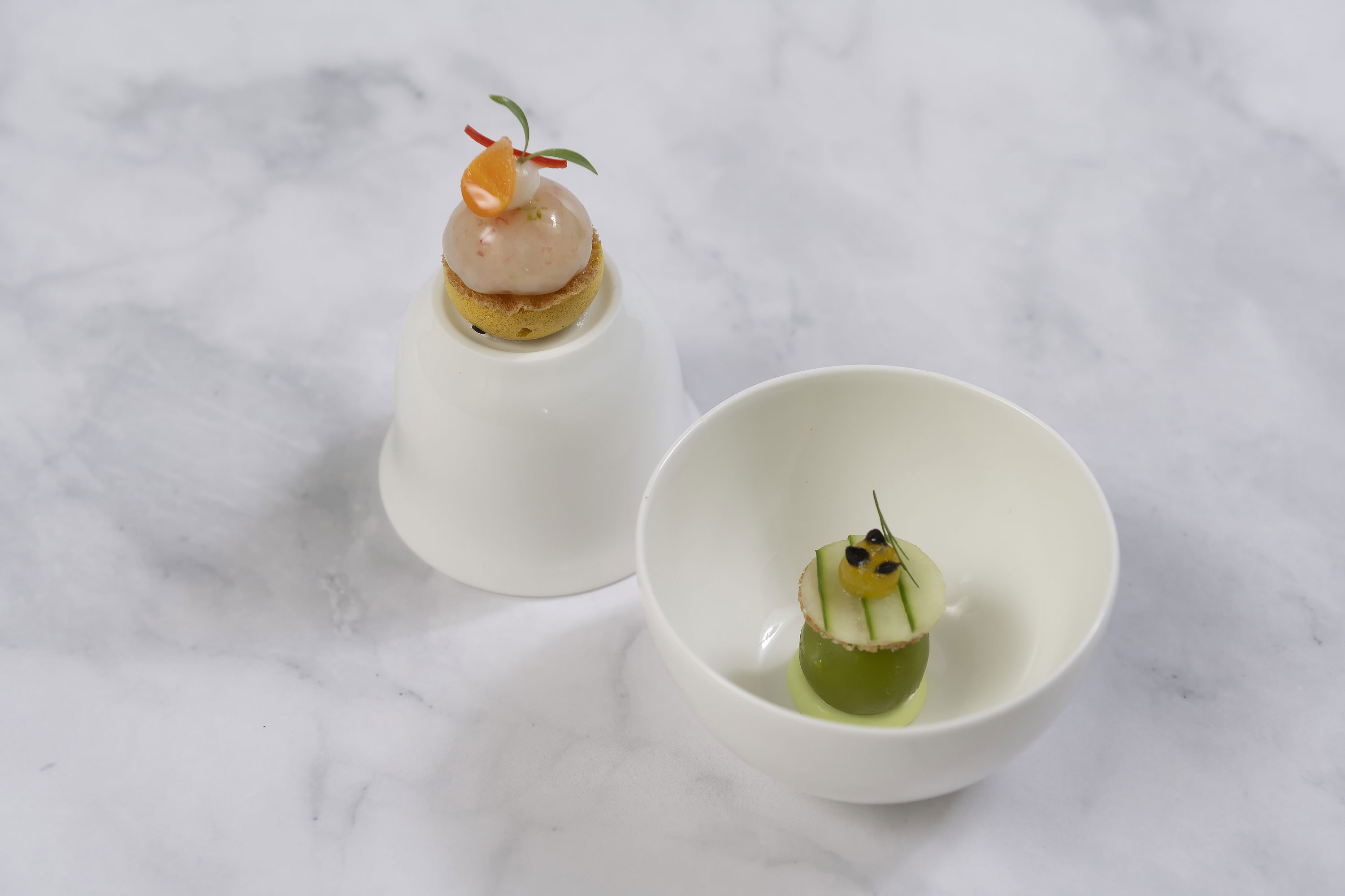 Starter Zwei kunstvoll angerichtete Amuse-Bouches in der Orangerie des Maritim Timmendorfer Strand auf weißem Geschirr.